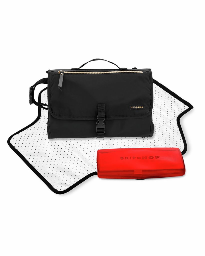 Zwarte luiertas met aankleedkussen en rode doos. Aankleedkussen met witte stippen. Skip Hop logo.