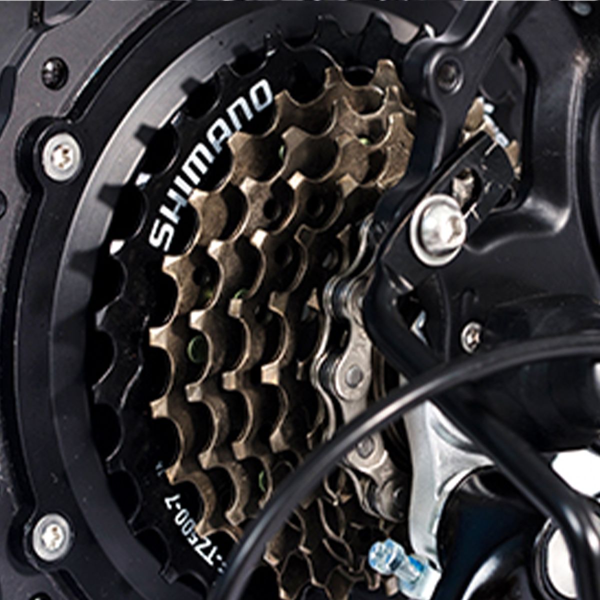 Close-up van de tandwielen. Opschrift SHIMANO. Meerdere tandwielen en ketting zichtbaar.