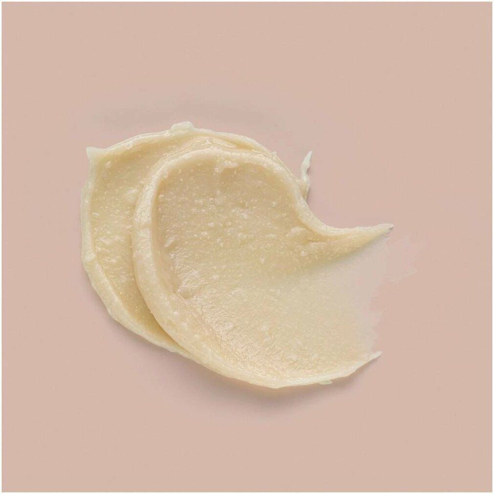 Échantillon de crème crémeuse avec des particules visibles sur fond clair.