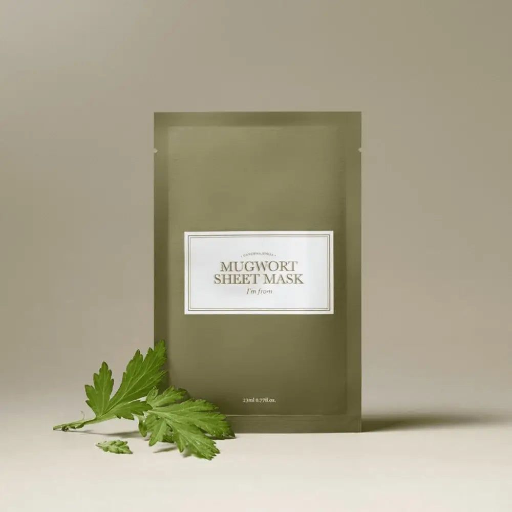 Masque en feuille vert avec étiquette blanche. Texte : MUGWORT SHEET MASK, I'm from. Une feuille à côté.