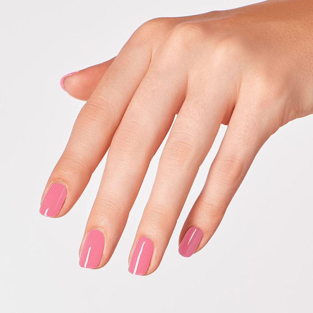 Main avec ongles vernis. Les ongles sont peints avec du vernis à ongles rose. La main est légèrement ouverte.