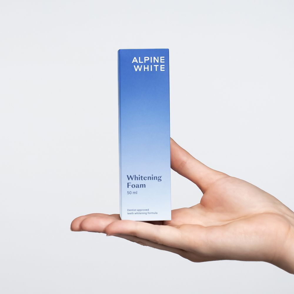 Hand houdt een doos met "ALPINE WHITE Whitening Foam". 50 ml.