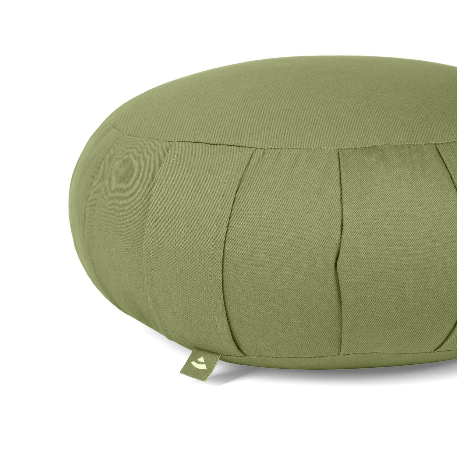 Gros plan d'un coussin de méditation vert olive avec plis et étiquette.