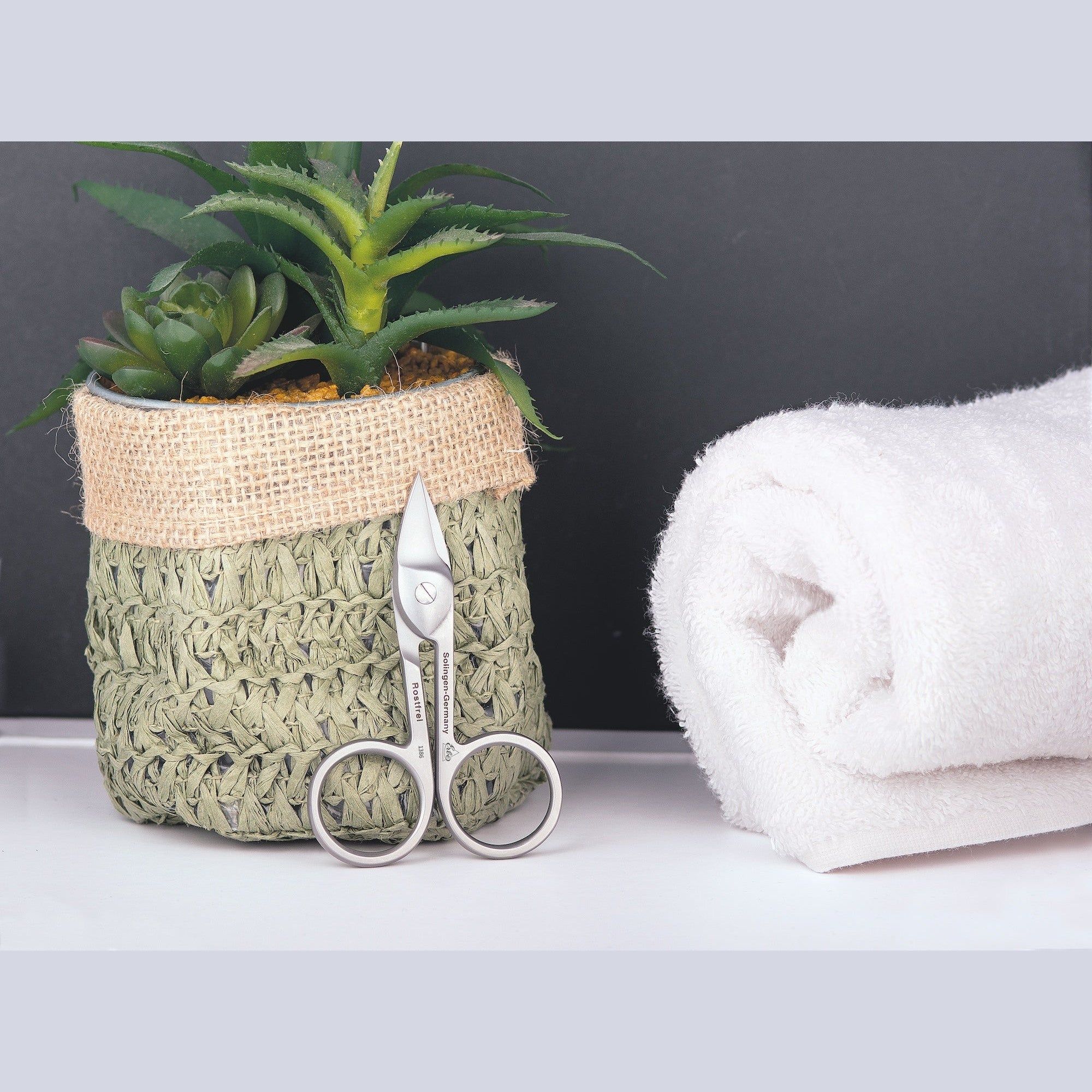 Nagelschaar naast een handdoek en een pot met plant. Productpresentatie. Achtergrond: zwart en wit.