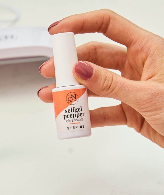 Main tenant un flacon à bouchon blanc. Étiquette avec logo PN, texte "selfgel prepper cleansing" et "STEP 01".