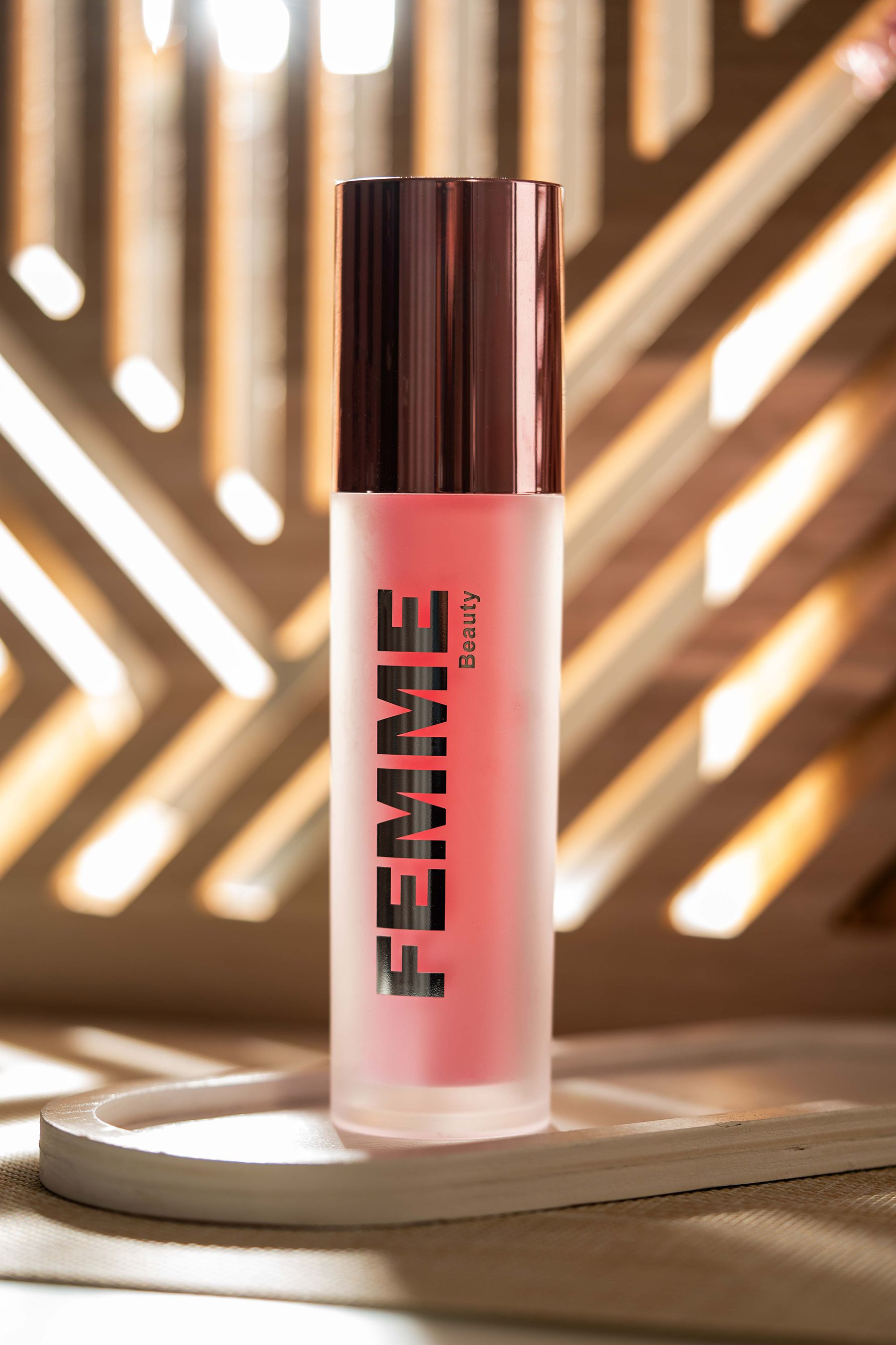 Fles met matte afwerking en roze inhoud, roségouden dop. Merk: FEMME Beauty.