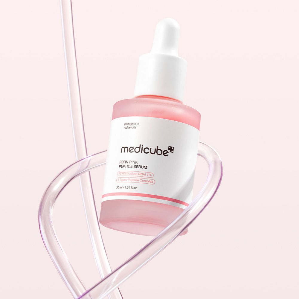 Flacon de Medicube PDRN Pink Peptide Serum avec pipette, entouré de tubes transparents.