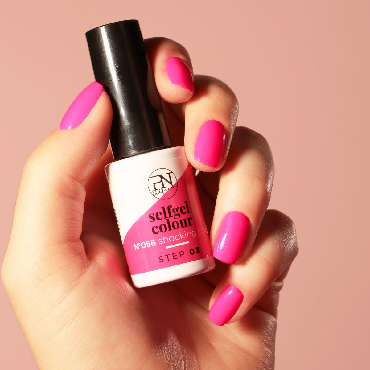 Main tenant un flacon de vernis à ongles et montrant des ongles vernis. Le flacon porte l'inscription "selfgel colour".