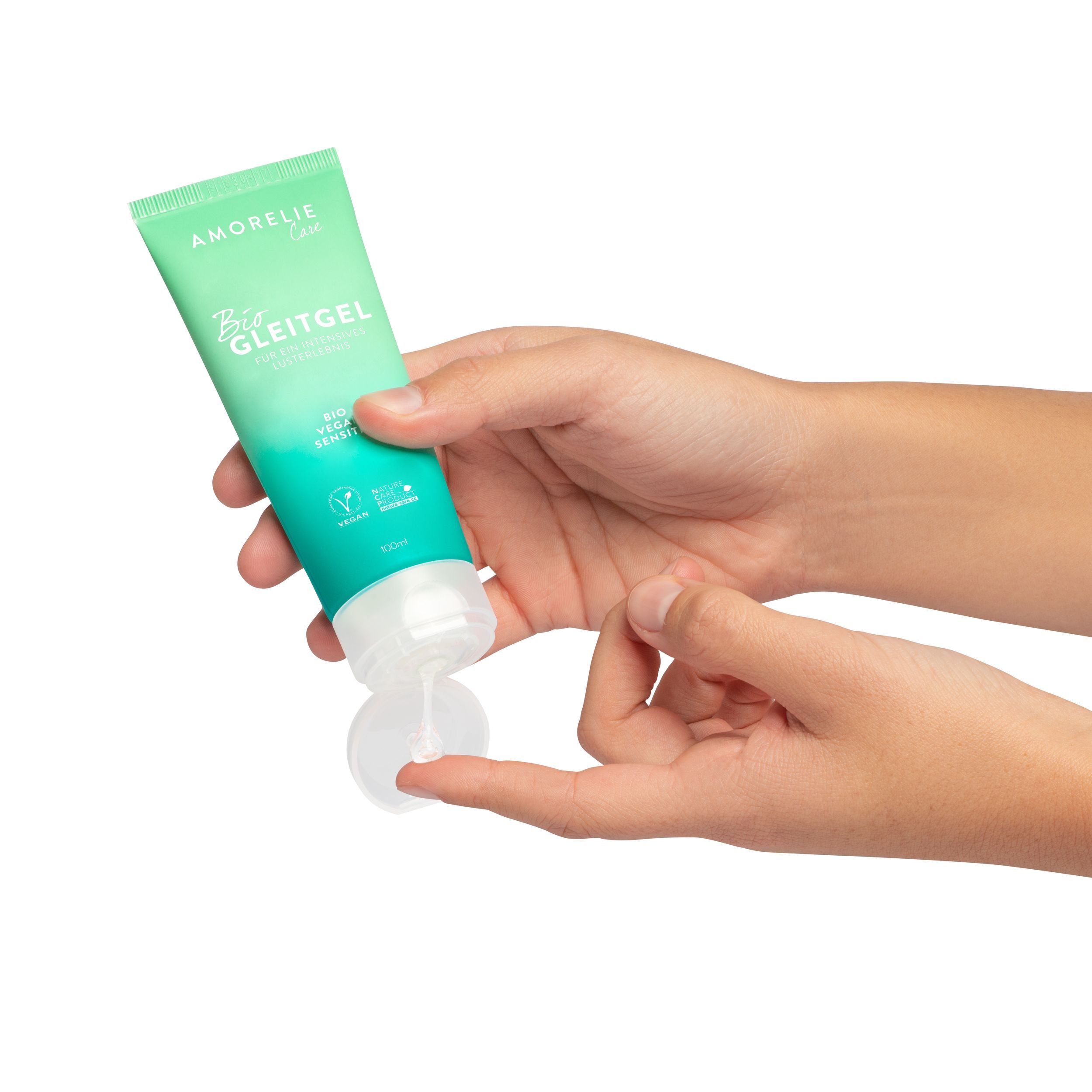 Handen houden groene tube vast. Dop open, product zichtbaar. Opschrift: AMORELIE Care, Bio Gleitgel, Bio Vegan Sensitiv. Vegan-keurmerk.