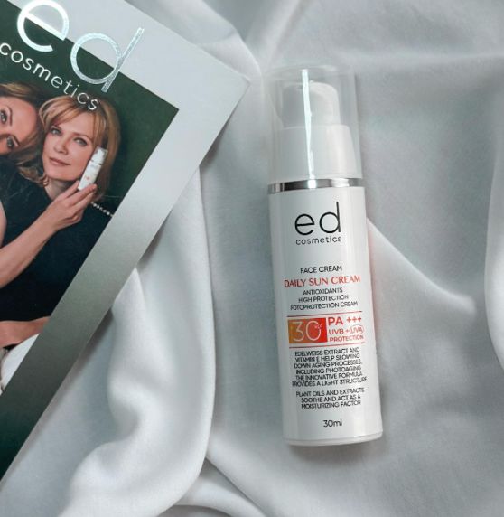 Flacon de crème solaire à côté d'un magazine. Inscription : ED cosmetics, Face Cream, Daily Sun Cream, SPF 30, PA+++.