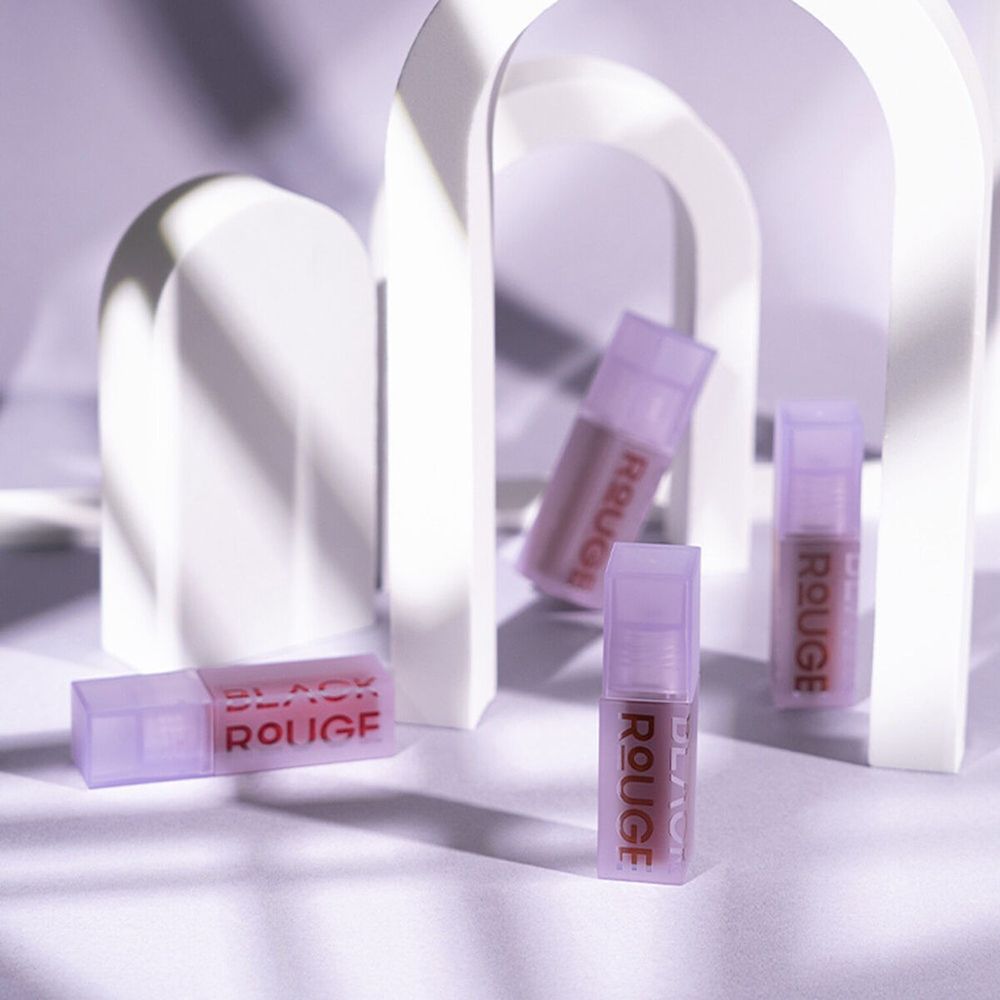 Plusieurs flacons de gloss avec des couvercles violets. Le texte BLACK ROUGE est visible.
