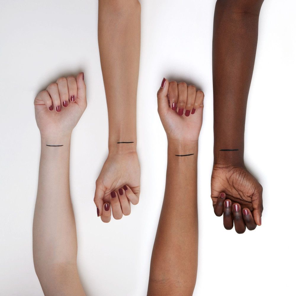 Quatre bras de teints différents. Traits d'eyeliner noirs sur les poignets.