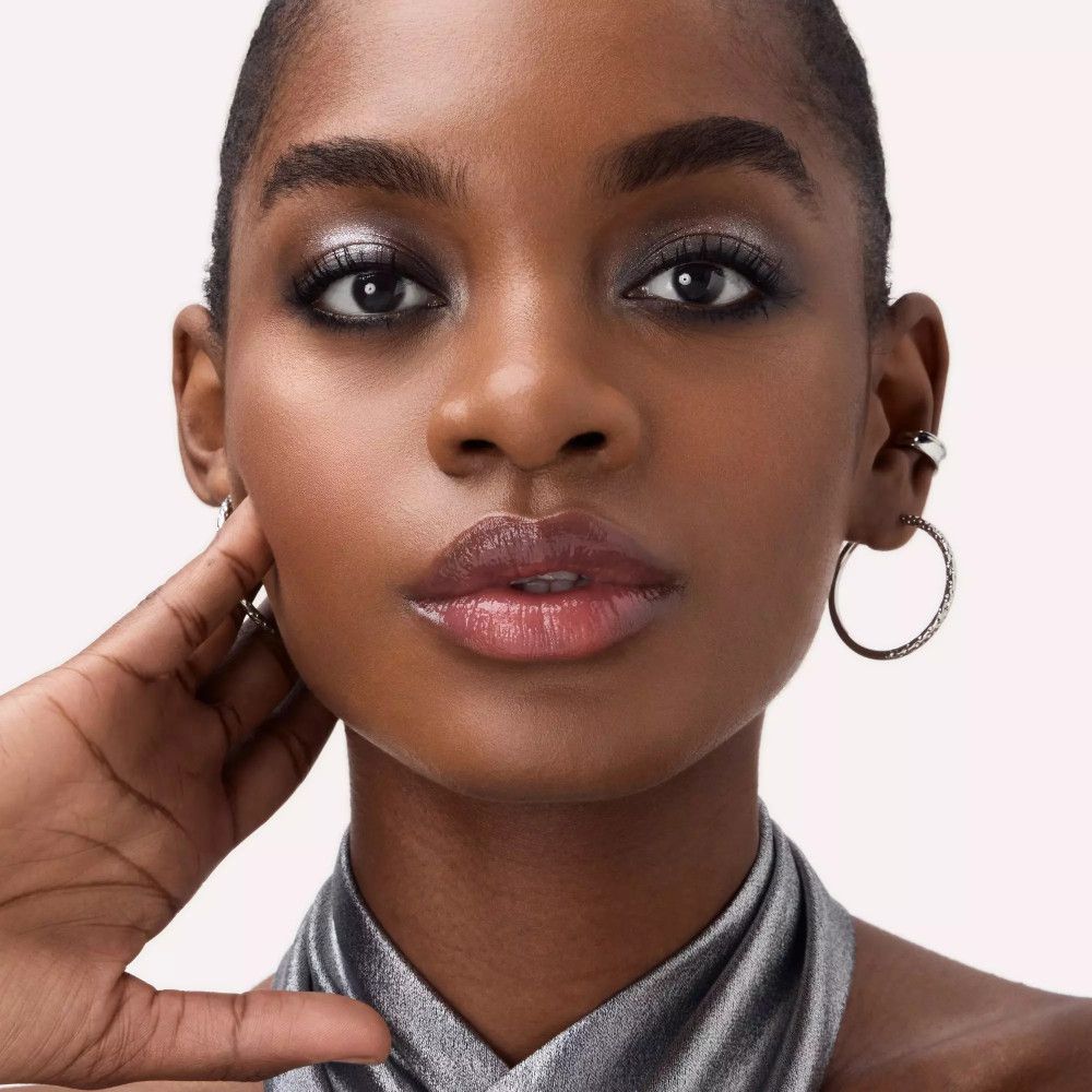 Gros plan d'une femme avec maquillage des yeux. Fard à paupières argenté et gris. Fond clair.