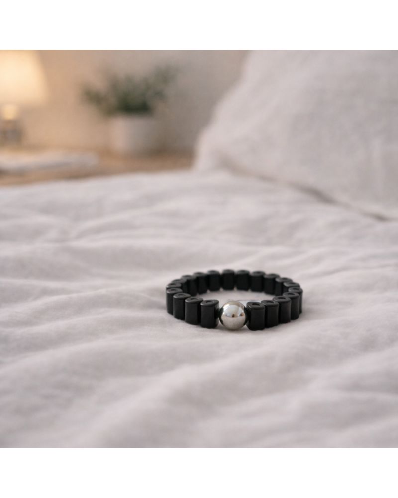 Bague noire avec bille argentée sur linge de lit blanc. Produit de bien-être.
