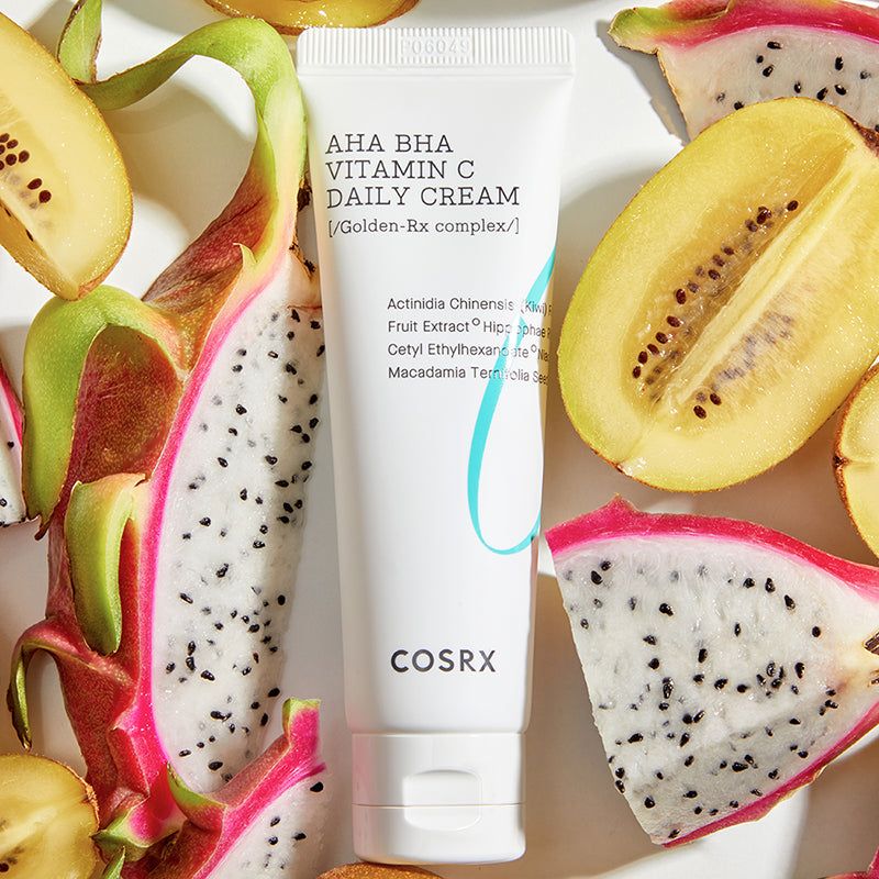 Witte tube AHA BHA Vitamin C Daily Cream, omringd door kiwi en drakenfruit.