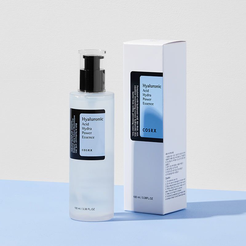 Fles en verpakking. Productnaam en merk COSRX op etiket en verpakking. Op blauwe achtergrond.