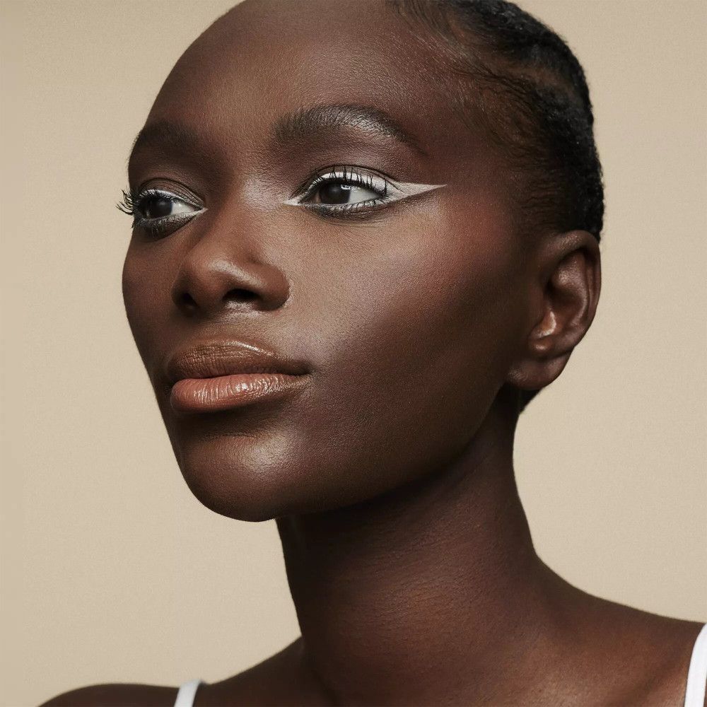 Gros plan d'un visage avec eye-liner blanc. Les lèvres sont légèrement teintées.