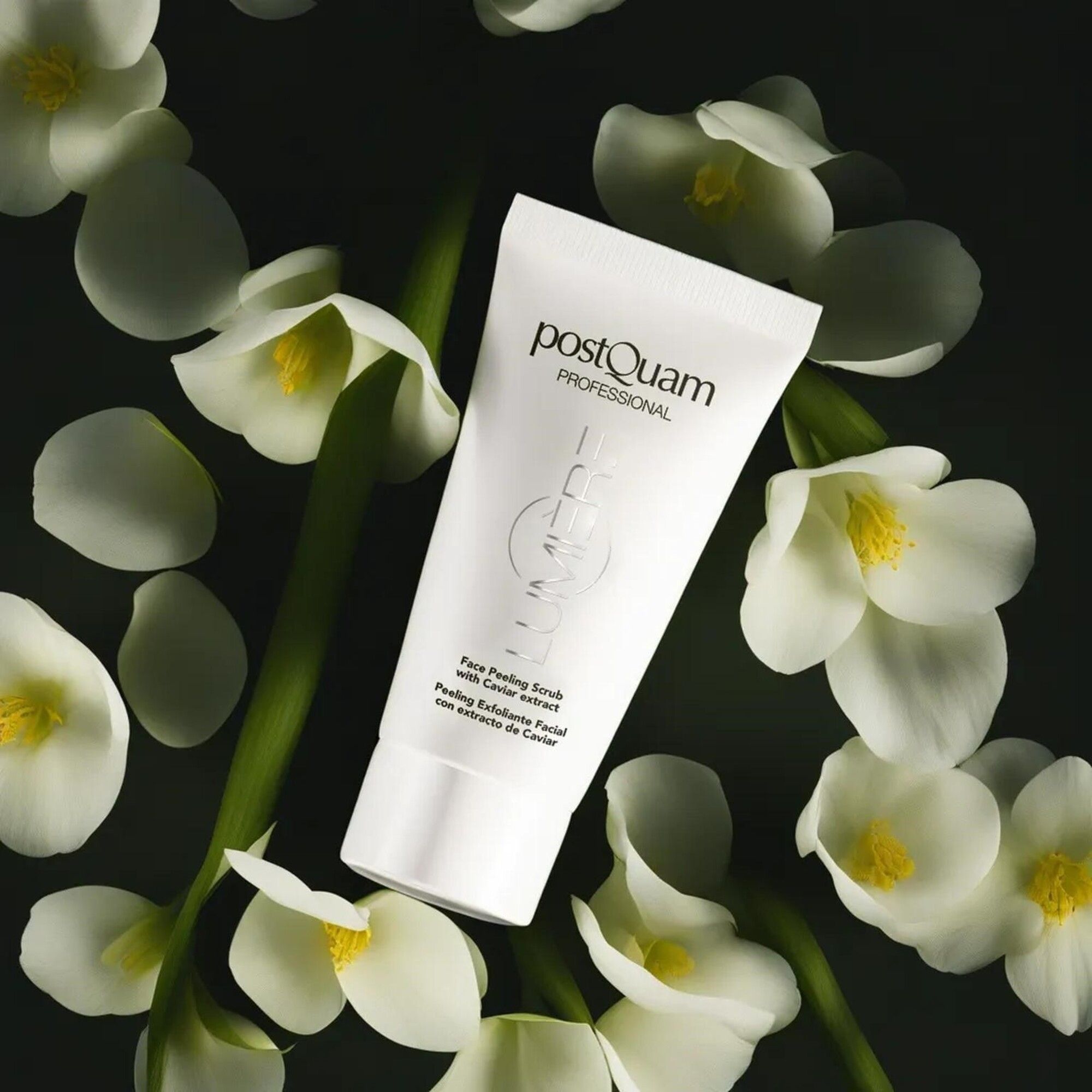 Witte tube met productnaam en tekst. Omringd door witte bloemen op donkere achtergrond. Tekst: Face Peeling Scrub with Caviar extract.
