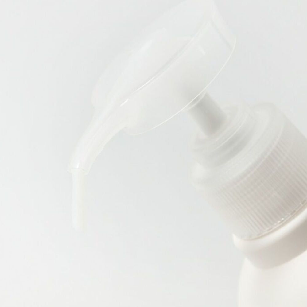 Gros plan d'un distributeur à pompe blanc avec du produit qui sort.