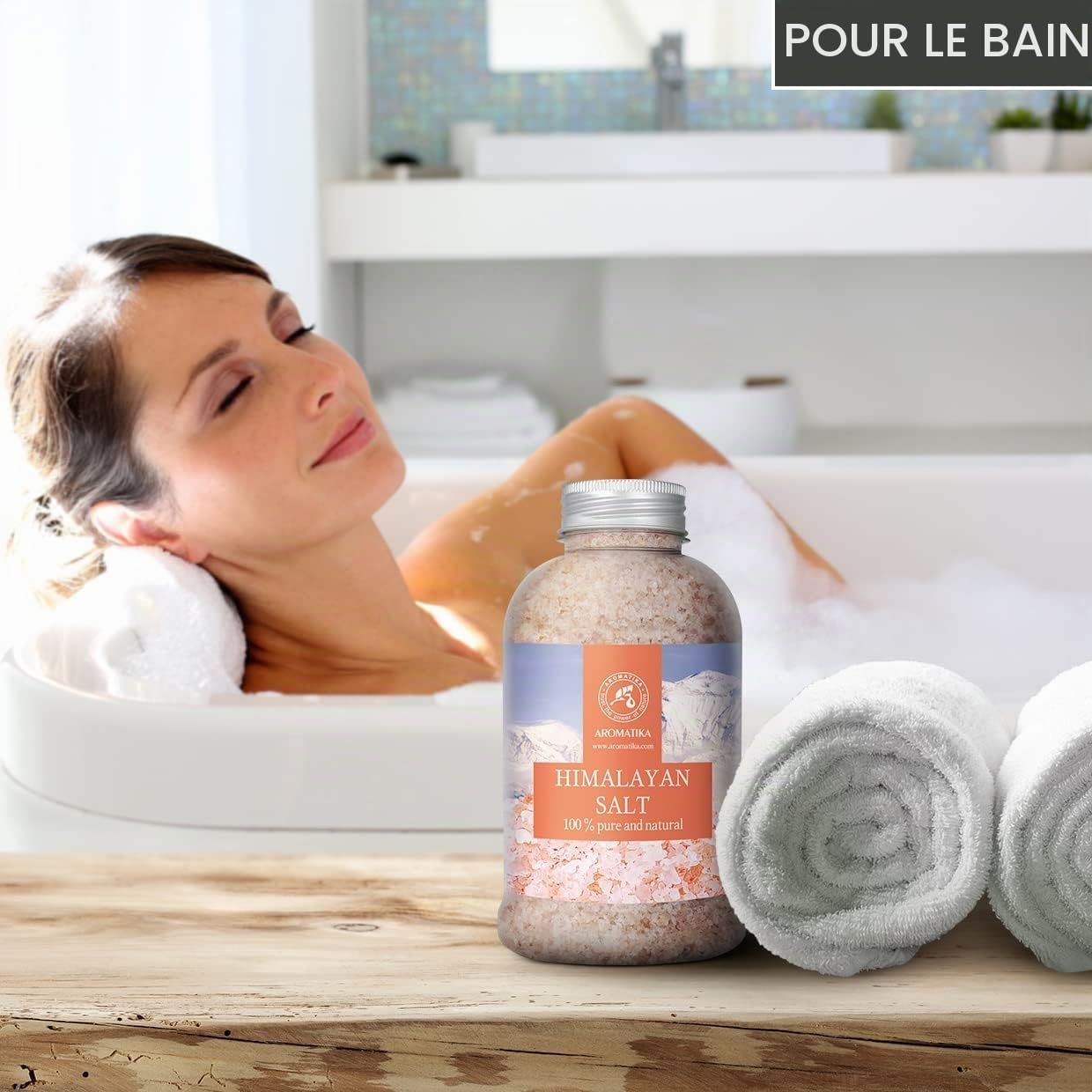 Bouteille de sel d'Himalaya pour le bain, avec deux serviettes roulées à côté.