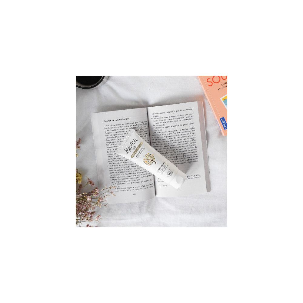 Tube de crème pour les mains Marilou Bio sur un livre ouvert. Inscription : Crème Mains, avec Aloe Vera et Argan. Certification bio.