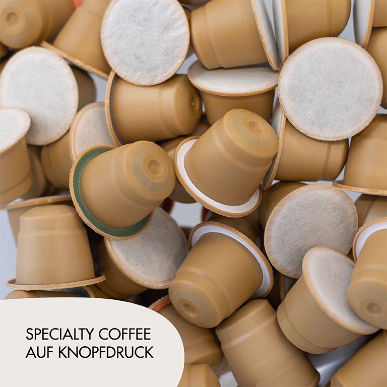 Tas de capsules de café. Inscription : Specialty Coffee auf Knopfdruck.