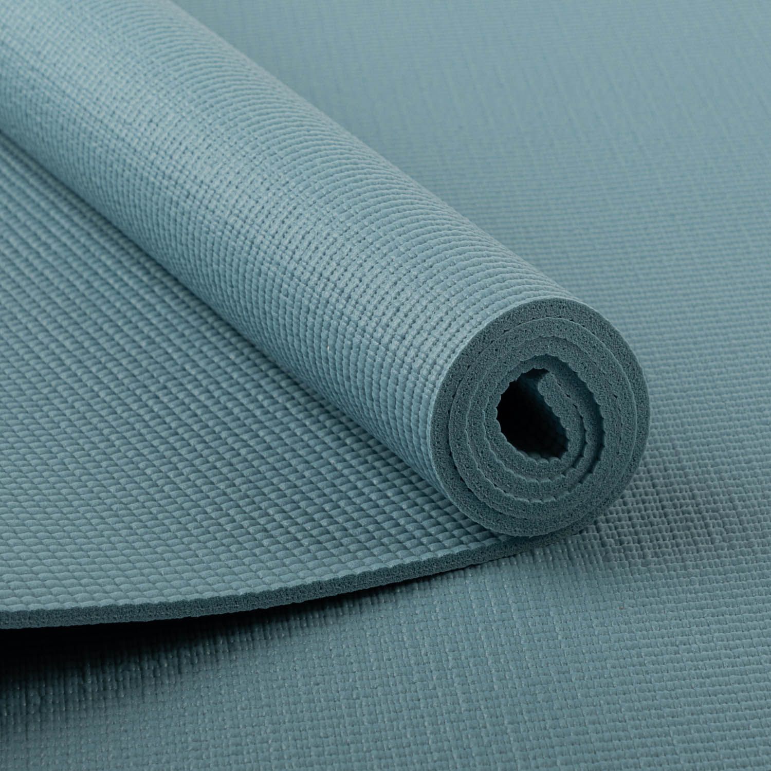 Tapis de yoga enroulé, bleu-vert. Surface en nid d'abeille. Vue détaillée du bord enroulé. Fond gris.