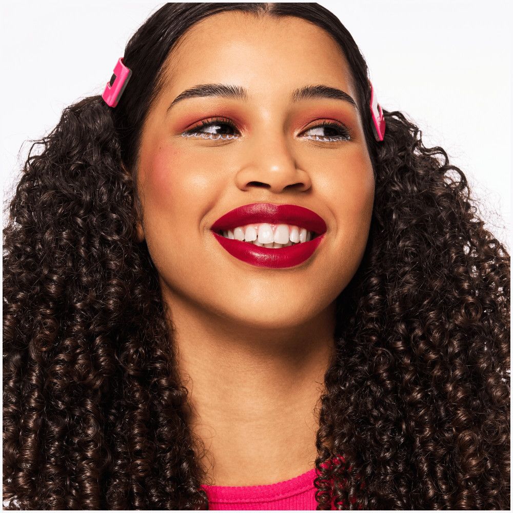 Femme souriante avec du rouge à lèvres rouge. Barrettes roses.