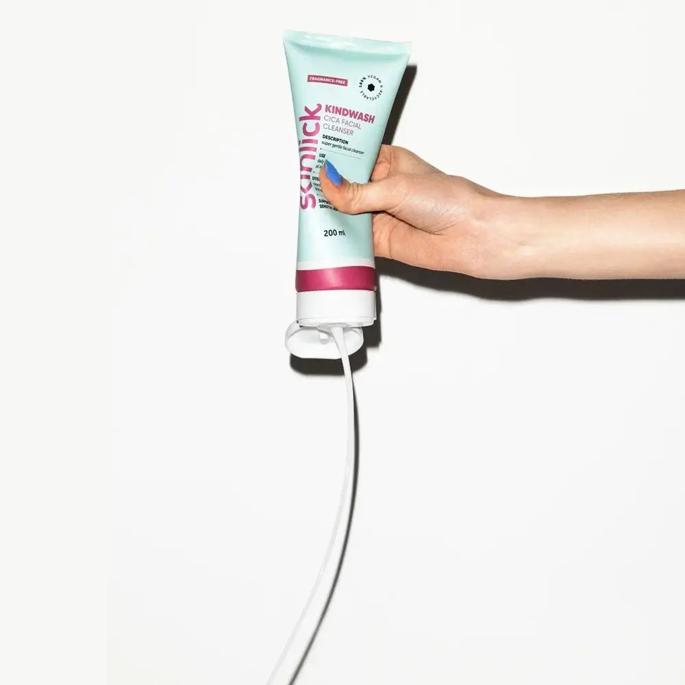 Tube vert clair avec bande rose. Texte: Kindwash, Cica Facial Cleanser. Produit tenu à la main. Fond blanc.