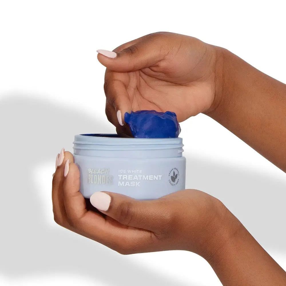 Mains retirant un masque bleu d'une boîte bleu clair "Bleach Blondes Ice White Treatment Mask".