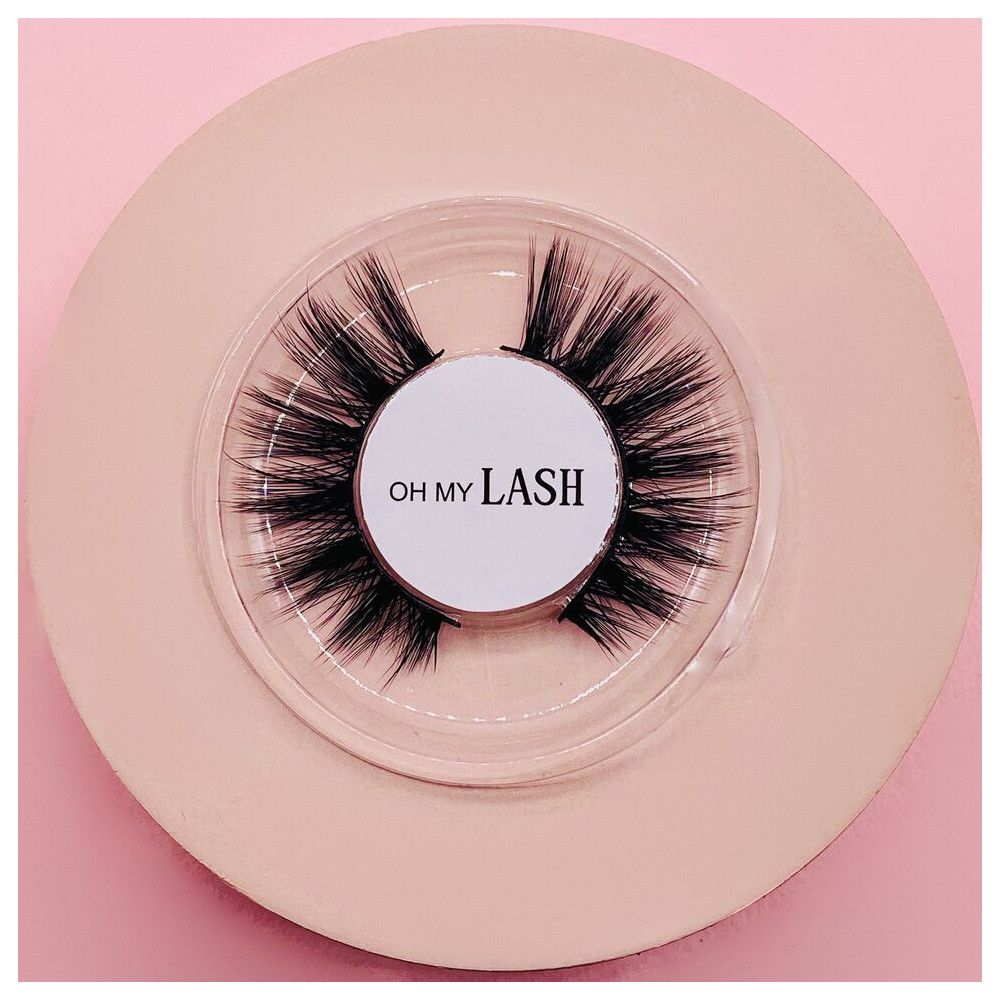 Faux cils dans un emballage rond transparent. Inscription : OH MY LASH. Sur fond rose.