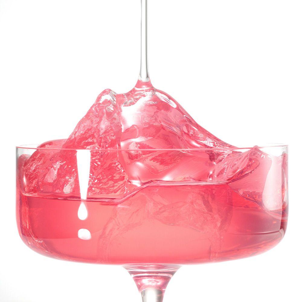 Roze vloeistof met ijsblokjes in een glas.