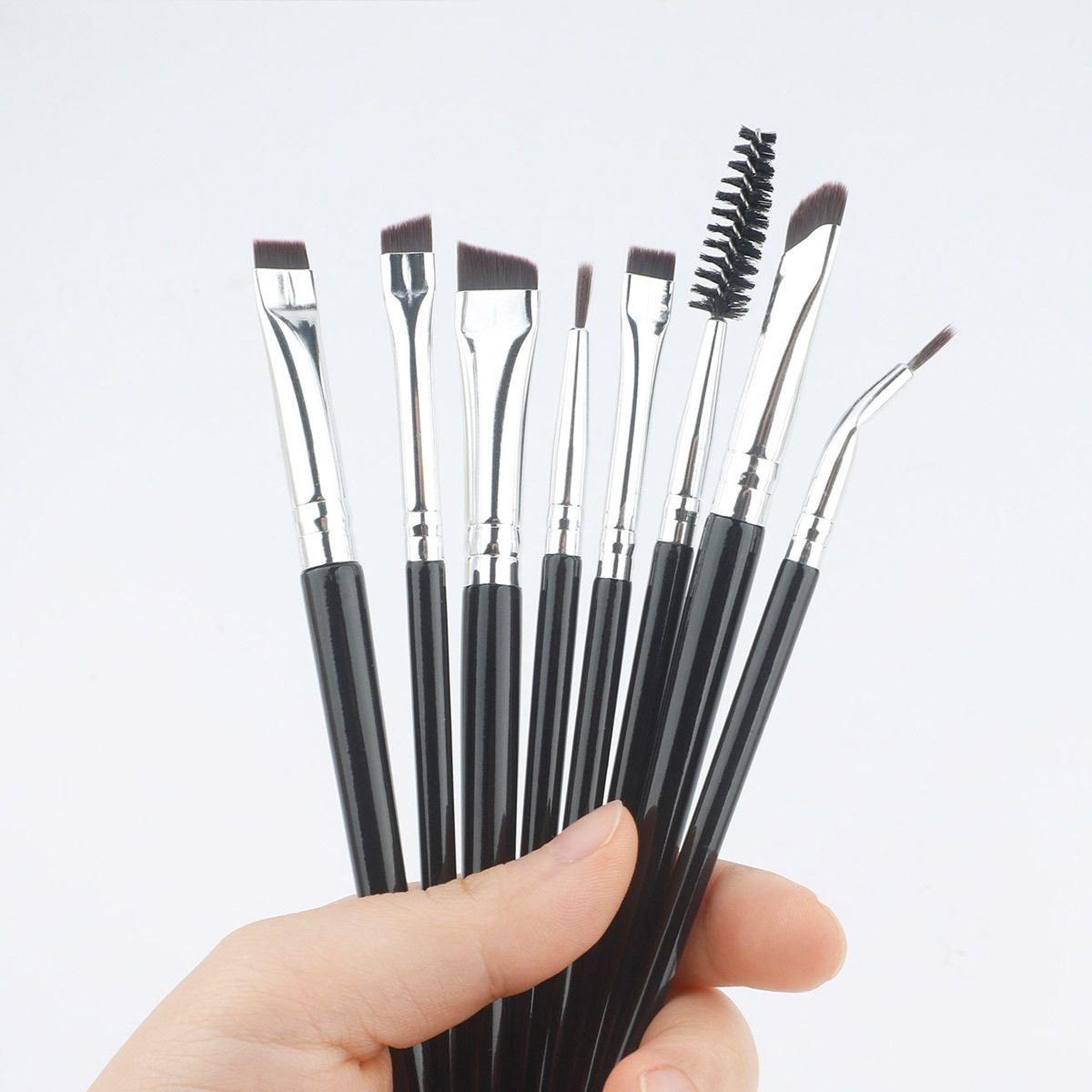 Un ensemble de huit pinceaux de maquillage noirs avec des manches argentés et des formes de poils variées.