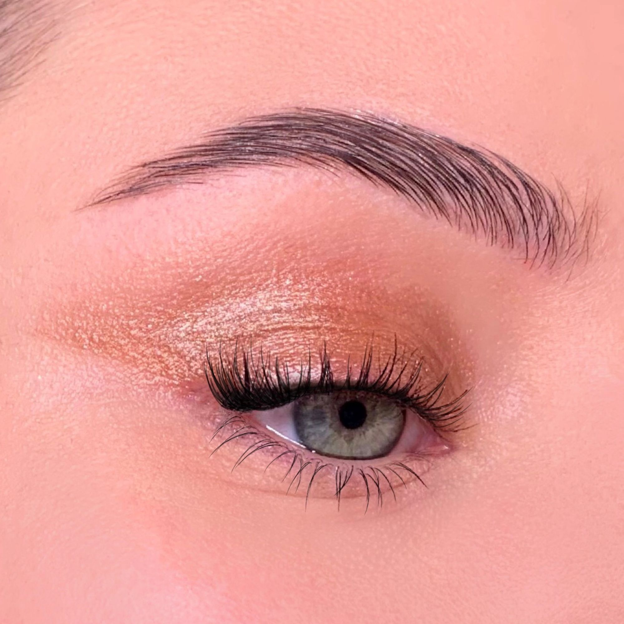 Close-up van een opgemaakt oog. Groene iris, wimpers, wenkbrauw. Oogschaduw. Huidtint.