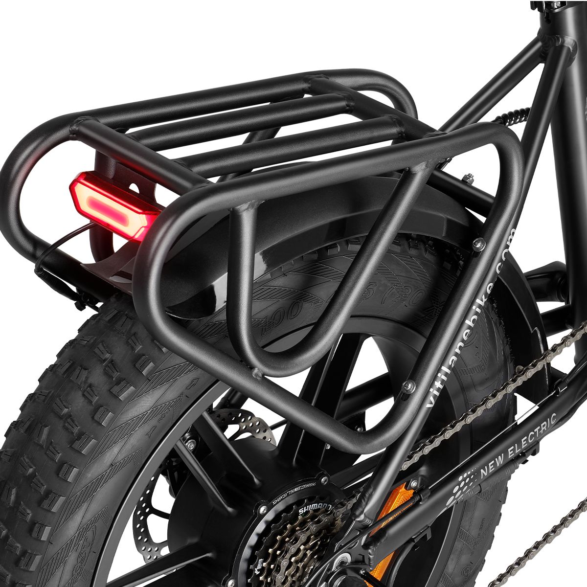 Porte-bagages noir avec feu arrière sur un vélo électrique. Garde-boue et parties de la roue arrière visibles.
