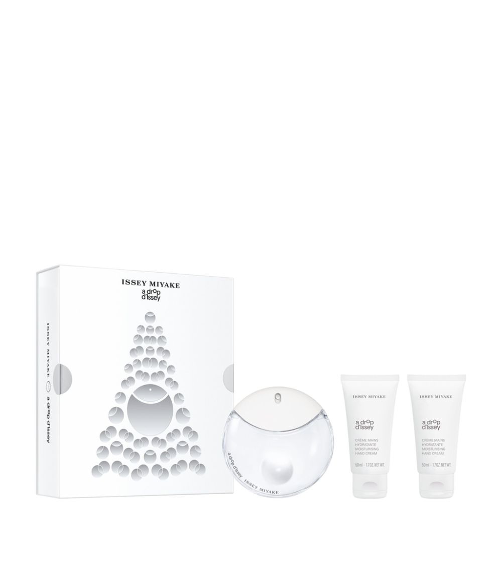 Coffret cadeau avec flacon de parfum, deux crèmes pour les mains et emballage. Flacon rond, transparent. Crèmes en tubes blancs. Emballage blanc avec logo.
