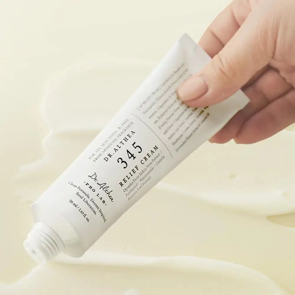 Main tenant un tube DR.ALTHEA 345 Relief Cream. Le produit est pressé.