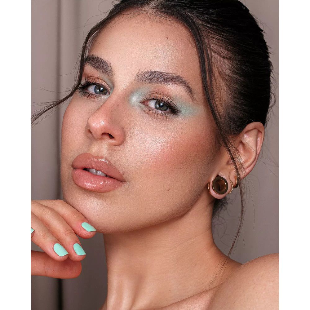 Gros plan d'une femme avec du maquillage. Elle touche son visage avec sa main.