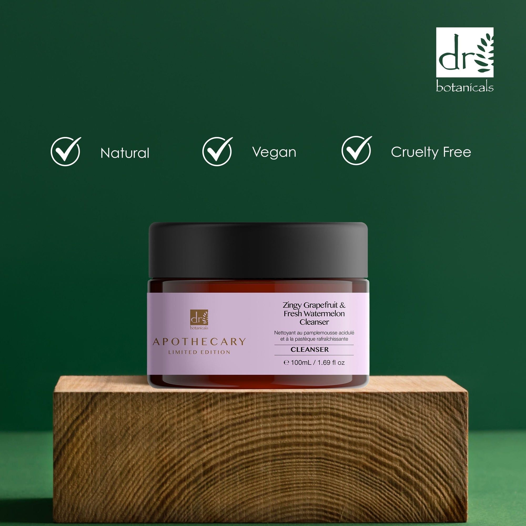 Bruine pot met zwarte deksel. Label met productnaam en merk. Opschrift: Natural, Vegan, Cruelty Free. Op houten blok.