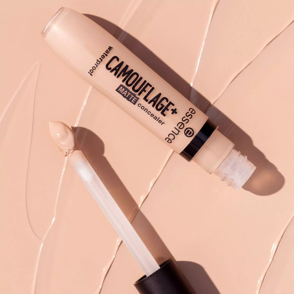 Tube de correcteur avec applicateur sur fond beige. Inscription: CAMOUFLAGE+ matte concealer, waterproof. Marque: essence.