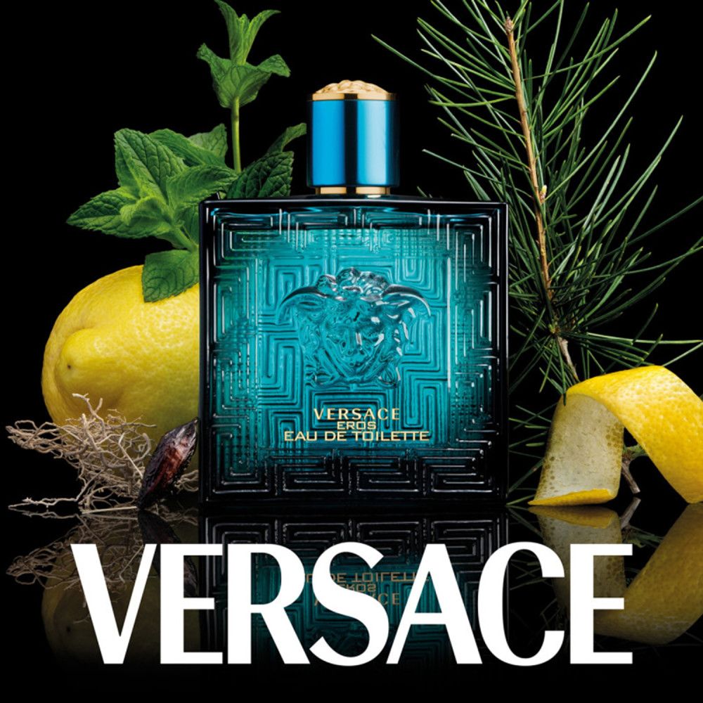 Flacon turquoise Versace Eros avec logo Méduse, entouré de citrons, herbes et branches de pin sur fond noir.