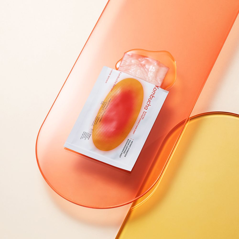 Emballage produit et masque sur surfaces colorées. Texte: Kombucha, Black Tea, Instant Hydration, Vegan Certified, Biodegradable Sheet.