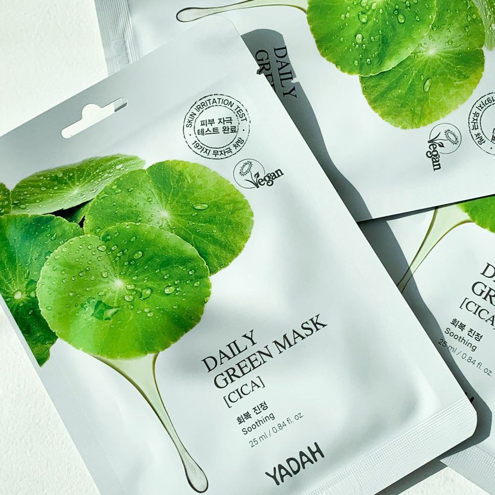 Plusieurs masques faciaux avec feuilles vertes et goutte. Texte: Daily Green Mask [Cica], YADAH, label Vegan.