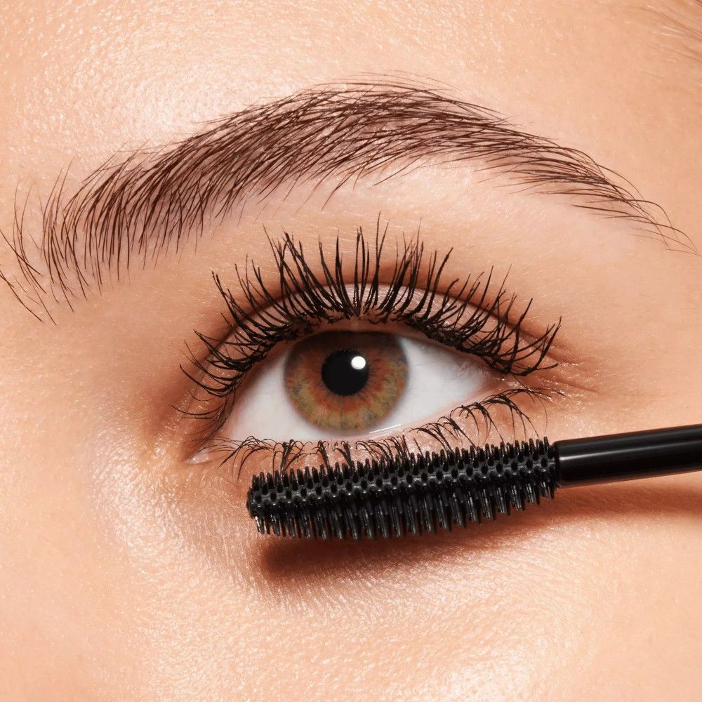 Œil avec cils maquillés. Une brosse à mascara est utilisée pour séparer et définir les cils.