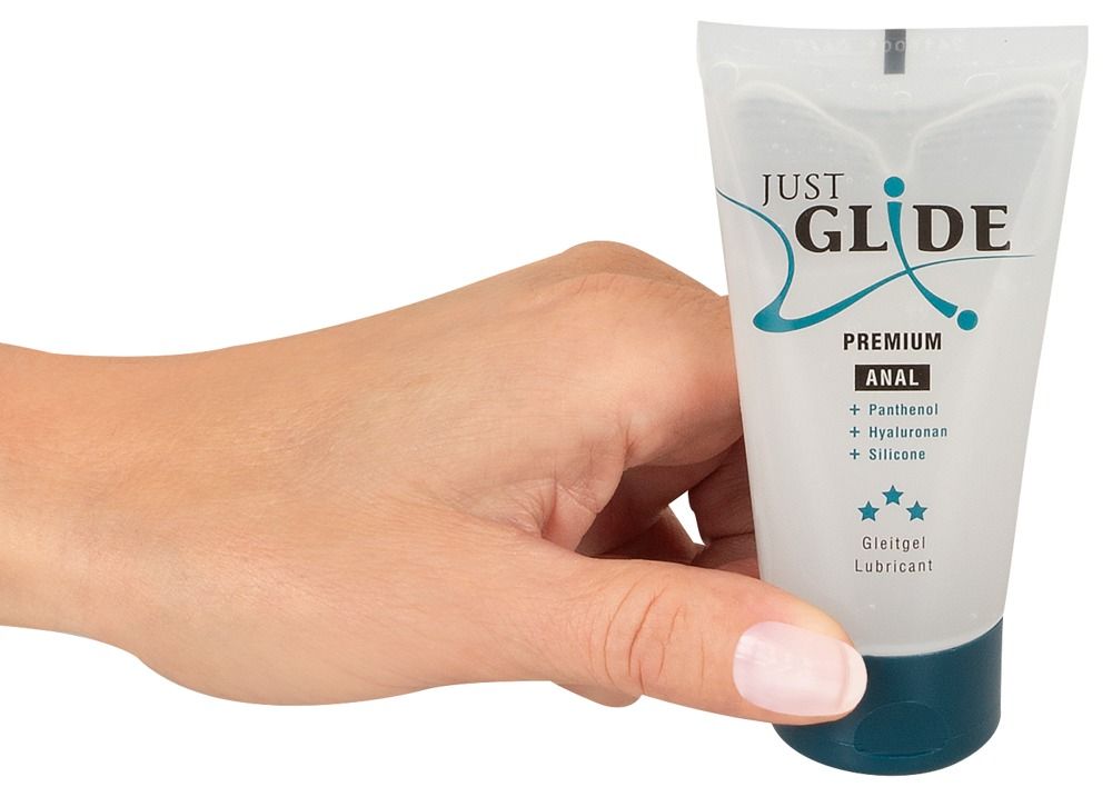 Hand houdt tube vast. Opschrift: Just Glide Premium Anal. Bevat Panthenol, Hyaluronan, Silicone. Medische glijmiddel. Transparante gel.