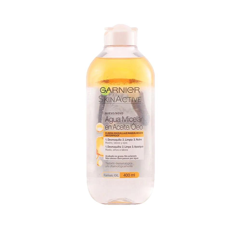 Transparante fles met gele vloeistof en witte dop. Opschrift Garnier SkinActive, Agua Micelar en Aceite/Óleo. 400 ml.