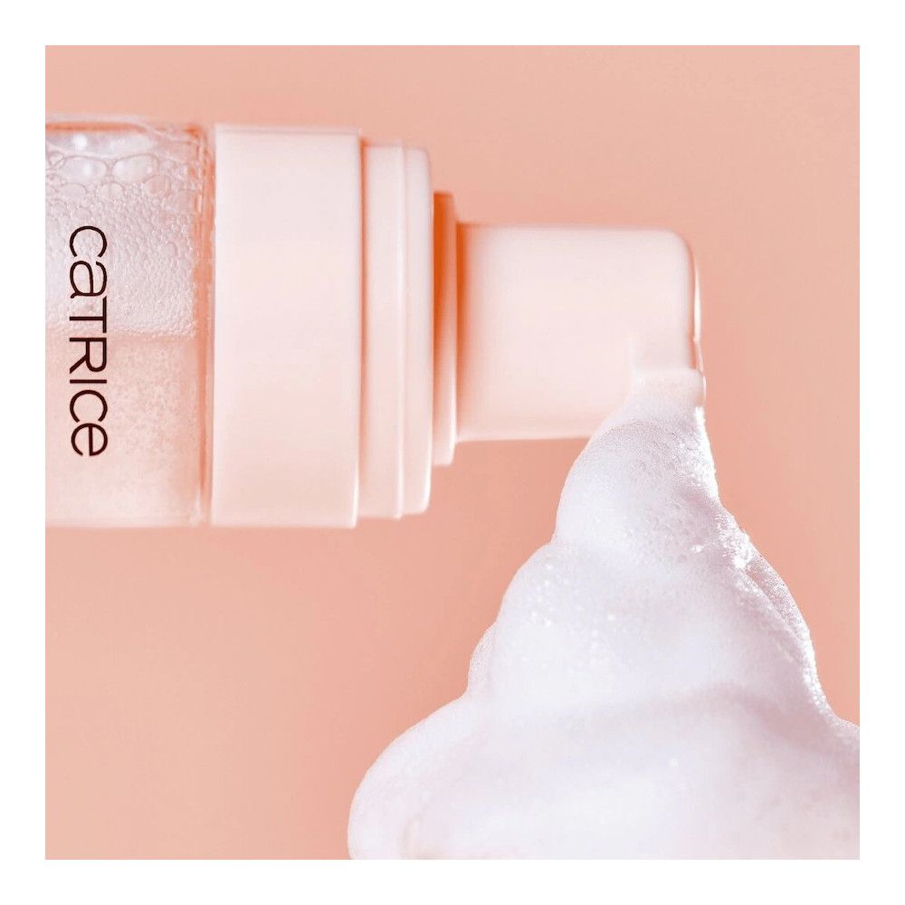 Close-up foundationfles met schuim. Opschrift: Catrice. Schuim wordt uit de fles geperst.