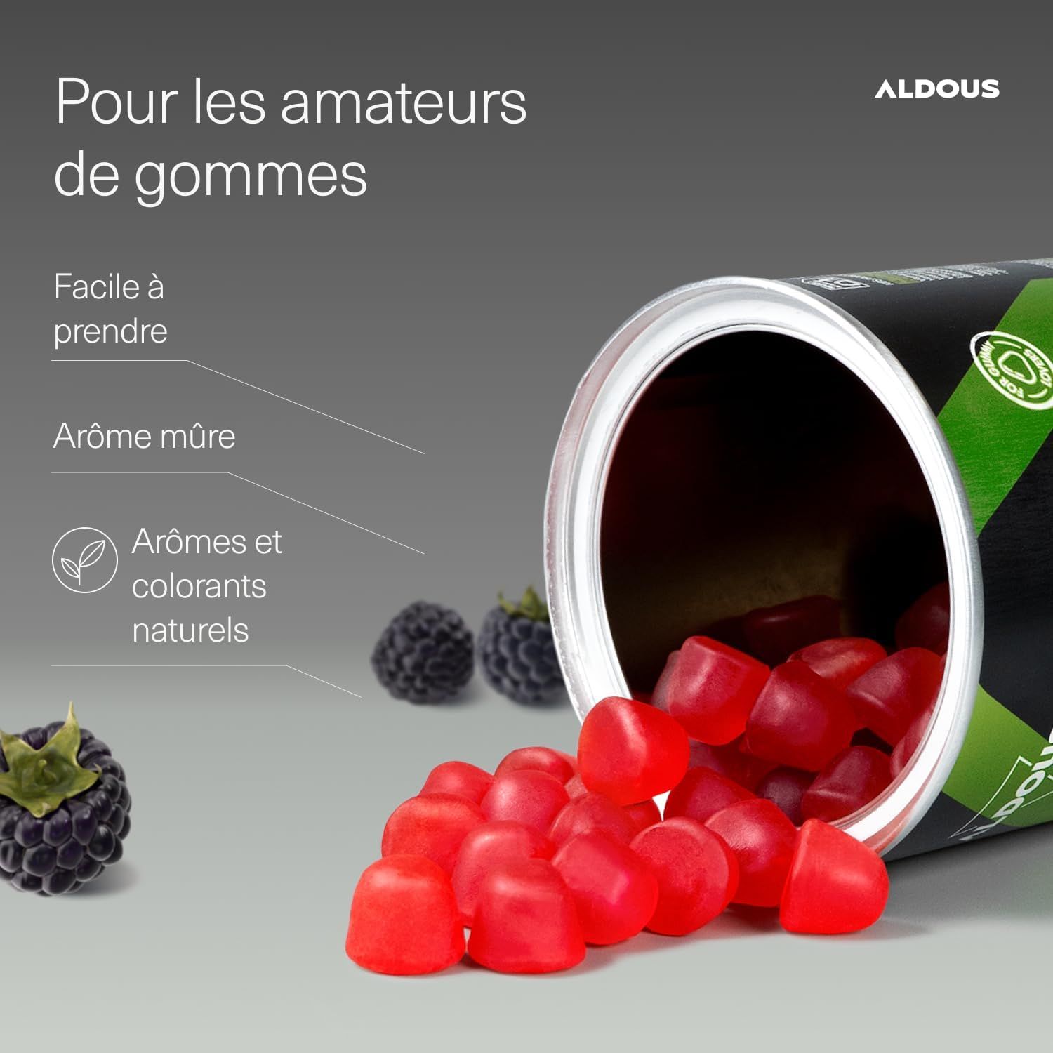 Gommes rouges saveur mûre renversées d'une boîte, avec des mûres à côté.