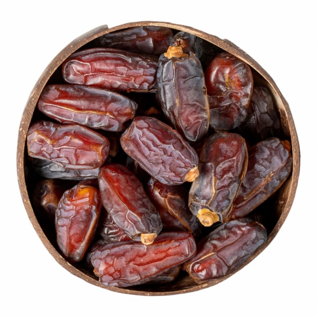 Ronde kom gevuld met dadels. Bovenaanzicht. Donkerbruine vruchten in een houten kom.