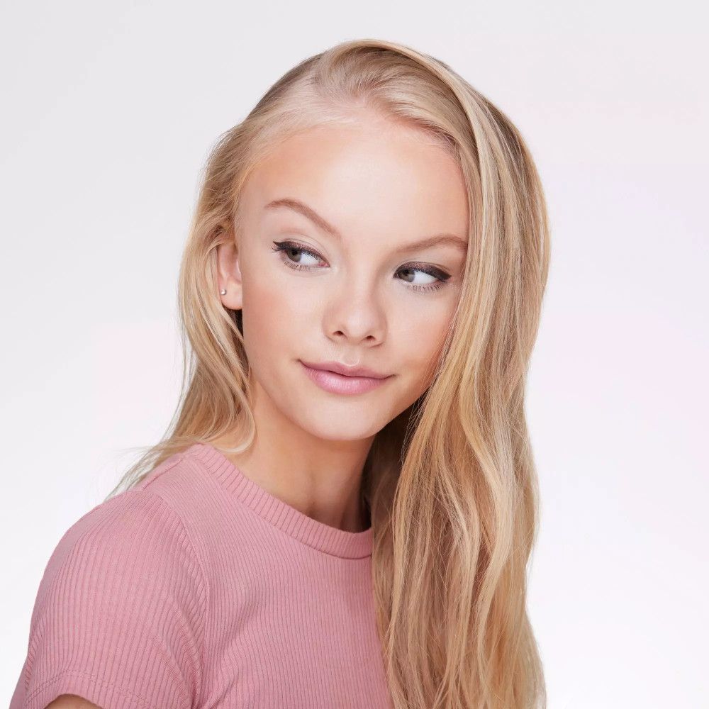 Portrait d'une jeune femme aux cheveux blonds. Elle porte un crayon pour les yeux. Haut rose.